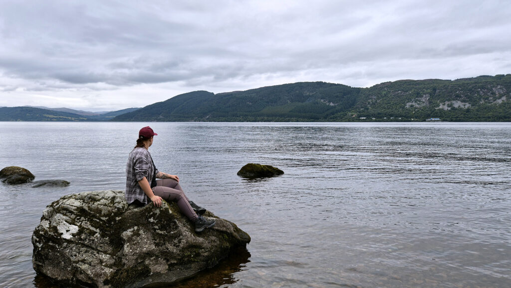 Ein Foto von mir auf einem Stein am Ufer des Loch Ness, wie ich auf das Wasser schaue